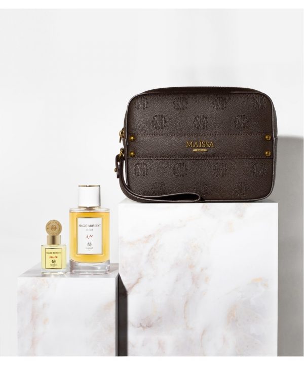 Dieses Bild zeigt das Parfüm-Set von Maison Maïssa mit dem Duft Magic Moment, dem dazugehörigen Duftöl und einer braunen, sehr hochwertigen Ledertasche. Das Set steht auf Marmortischen, vor einer weißen Wand