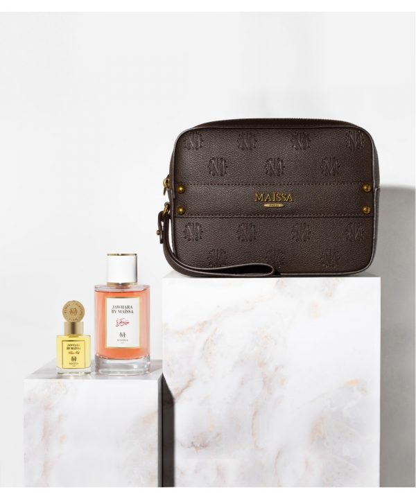 Dieses Bild zeigt das Parfüm-Set von Maison Maïssa mit dem Duft Jawhara, dem dazugehörigen Duftöl und einer braunen, sehr hochwertigen Ledertasche. Das Set steht auf Marmortischen, vor einer weißen Wand